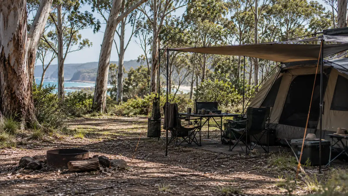 Tent, chairs and table under an awning at a eucalypt forest campsite above the coast